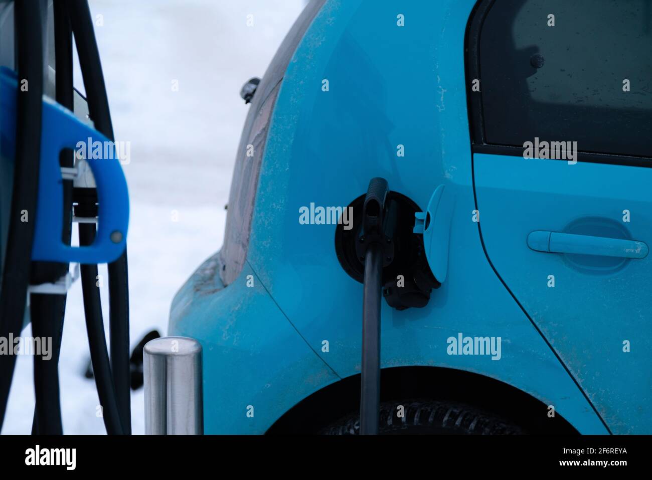 Charger plug inserted in electric car on snowy winter background. Green ...