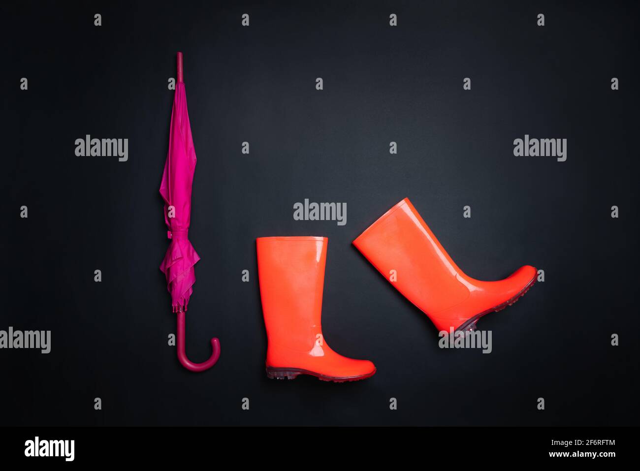 Rubber shoes and umbrella isolated on black background. Rain season and