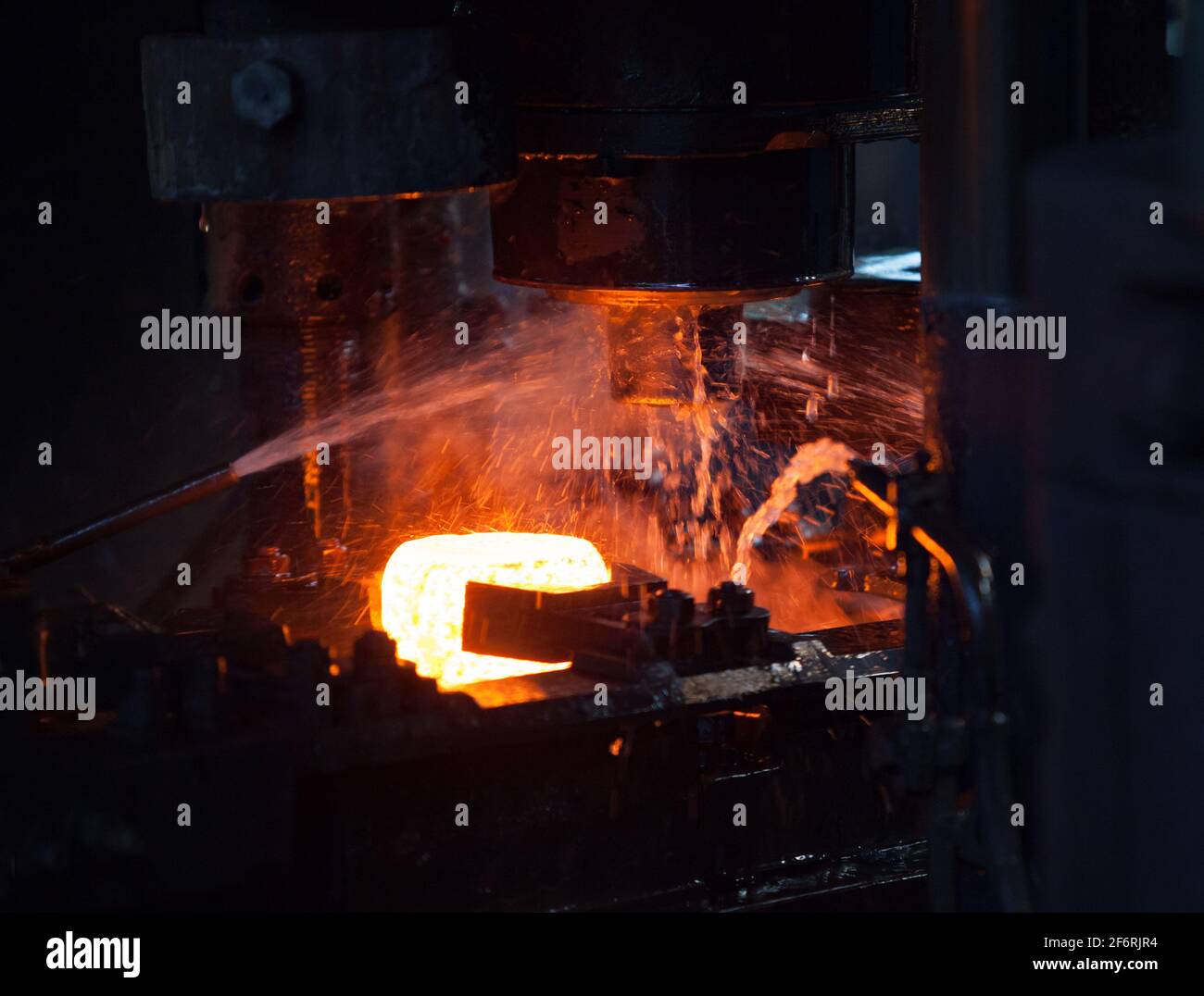 Bearing plant. Stamping of the inner ring of the bearing on a mechanical press. Water cooling of the metal.White hot metal Stock Photo