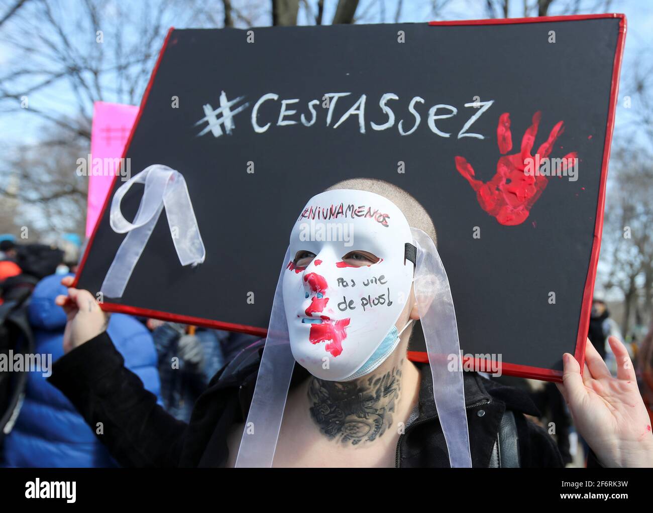 A person wears a mask that reads "Not one more" and a sign stating "That's  enough" as people march in protest against domestic violence, after several  women in the province were killed