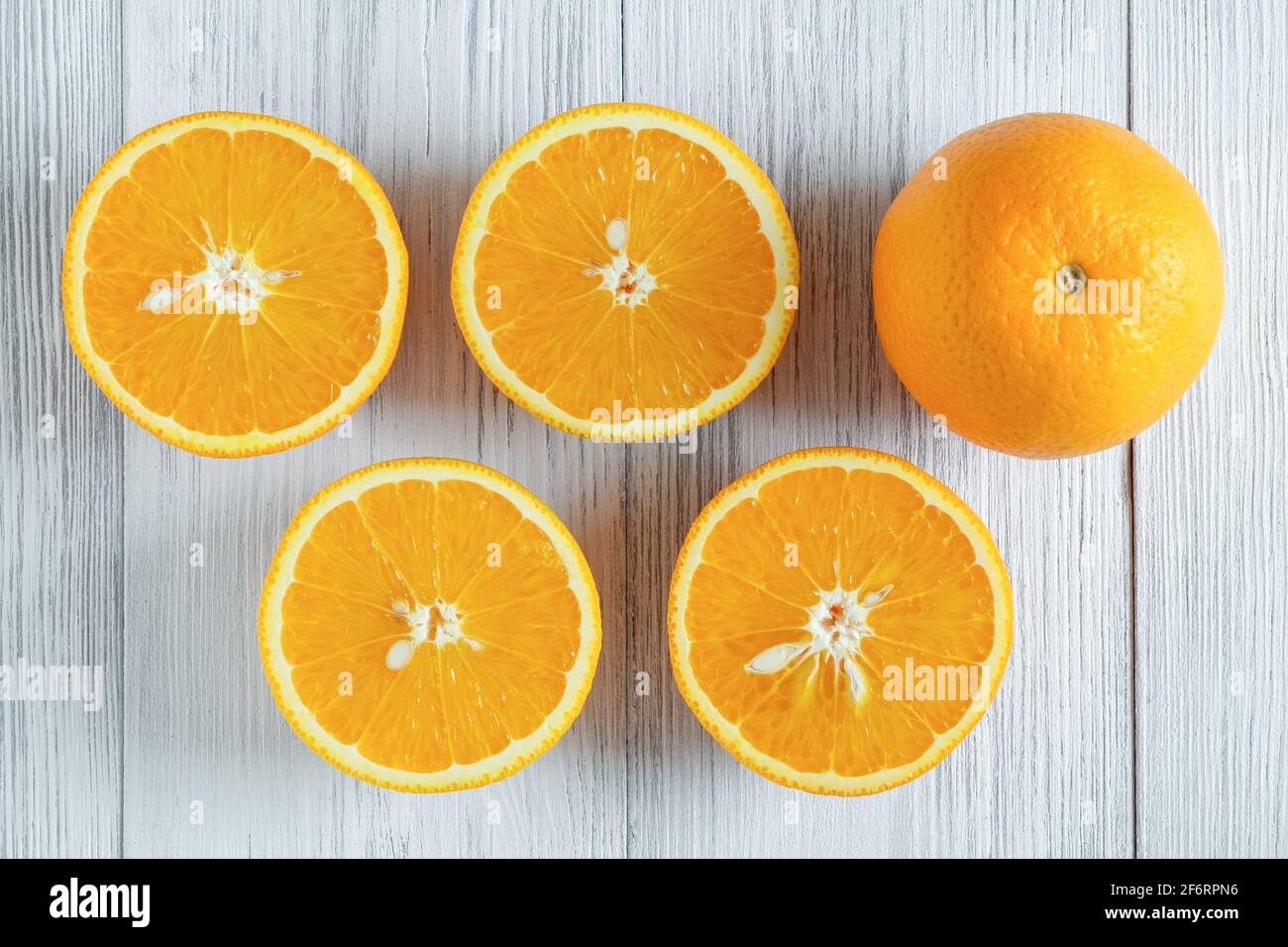 Close-up of whole and sliced oranges on a light wooden surface. Selective focus. Stock Photo