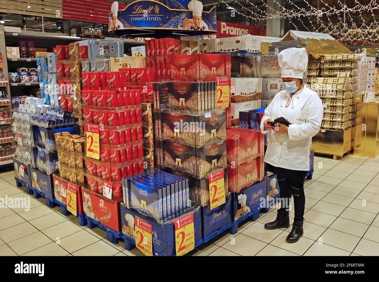 A chocolate 'chef' prepares a display in a supermarket while wearing mask. Stock Photo