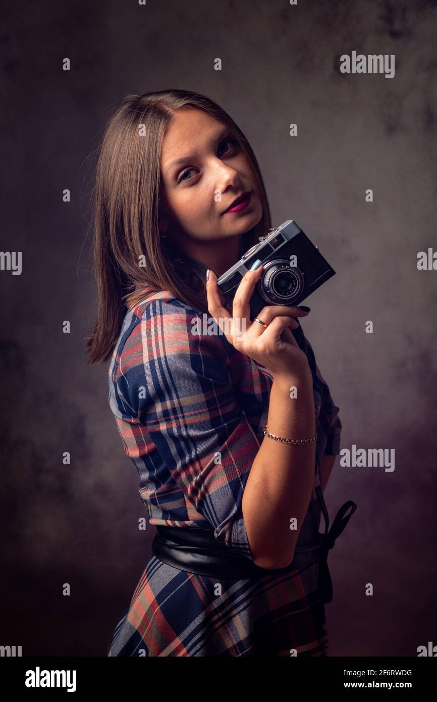Girl photographer with retro camera, studio photography on gray background. Stock Photo