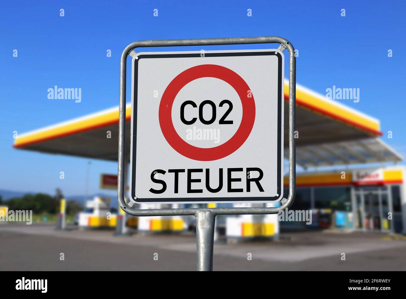 Symbol image introduction of the CO2 tax in Germany 2021: Traffic sign with lettering CO2 tax and gas station in the background. Stock Photo