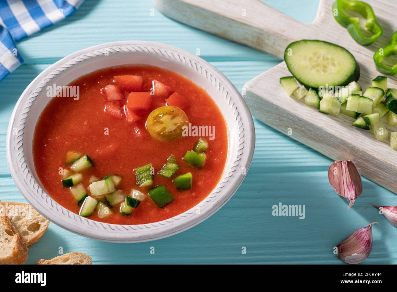 Gazpacho Andaluz is an Andalusian tomato cold soup from Spain with cucumber, garlic, pepper on light blue background. Stock Photo