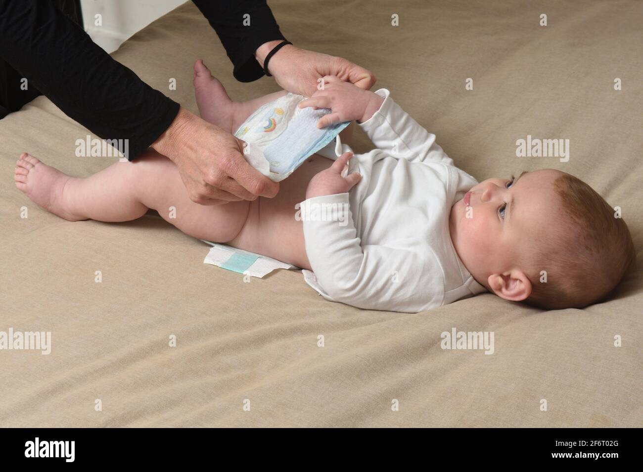 changing the diaper on the baby who is lying in bed Stock Photo Alamy