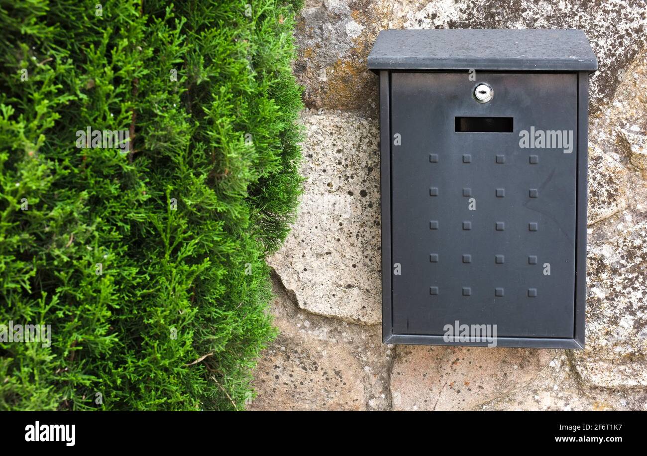 Black metal mailbox attached on cottage wall house. Selective focus. Stock Photo