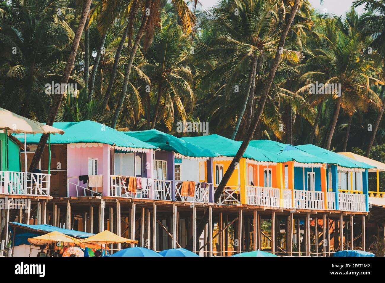 Canacona, Goa, India. Famous Painted Guest Houses On Palolem Beach Against Background Of Tall Palm Trees In Sunny Day. Stock Photo