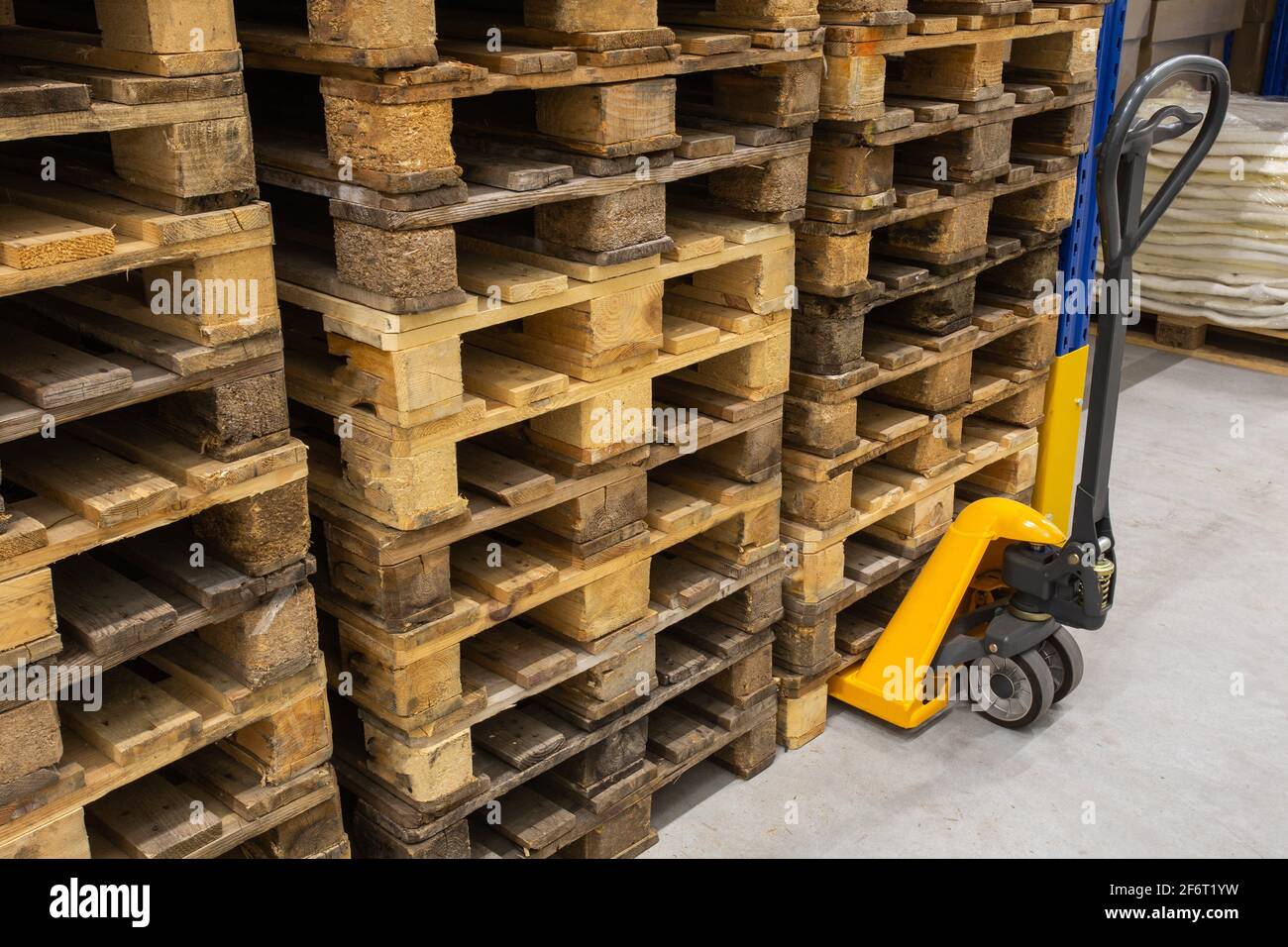 Hand pallet truck with stack of wooden pallets. Warehouse equipment