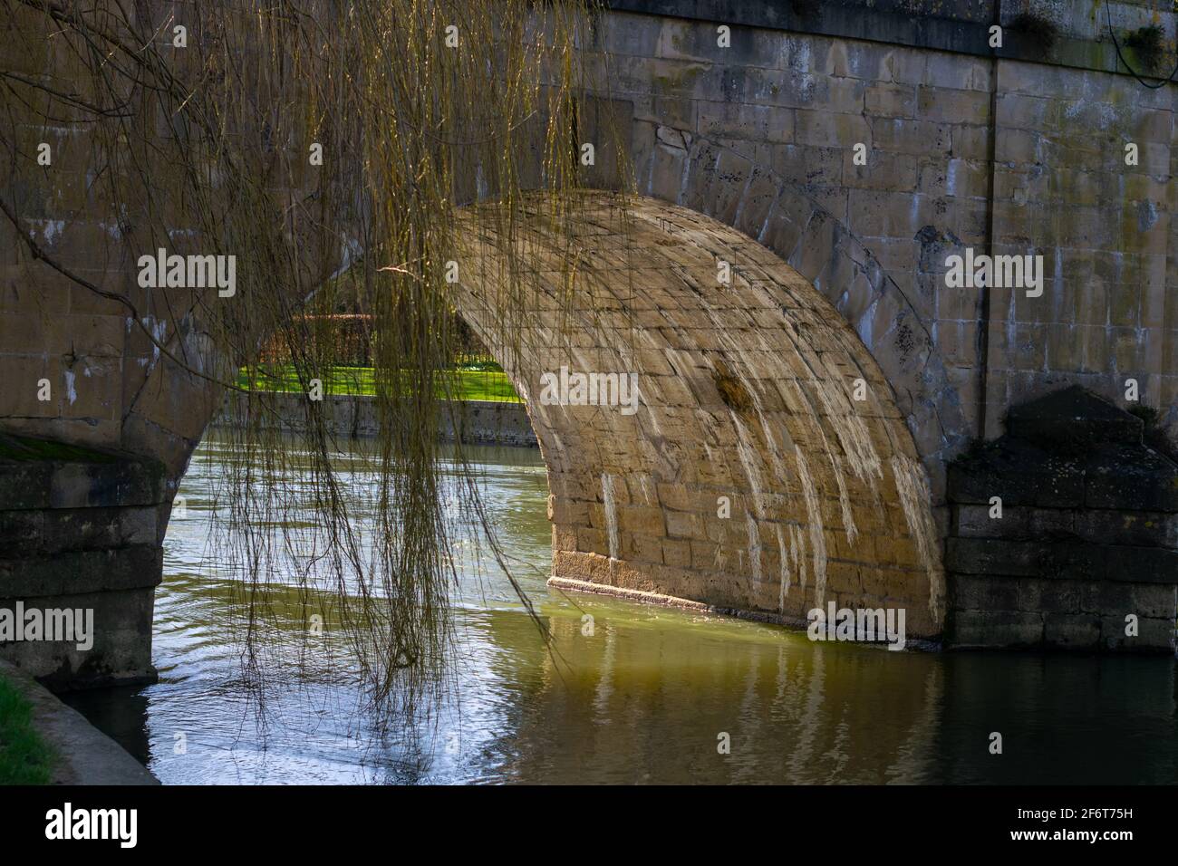 Arch under the bridge with sun reflections from the river, closeup on the part of the stone bridge over the river Stock Photo