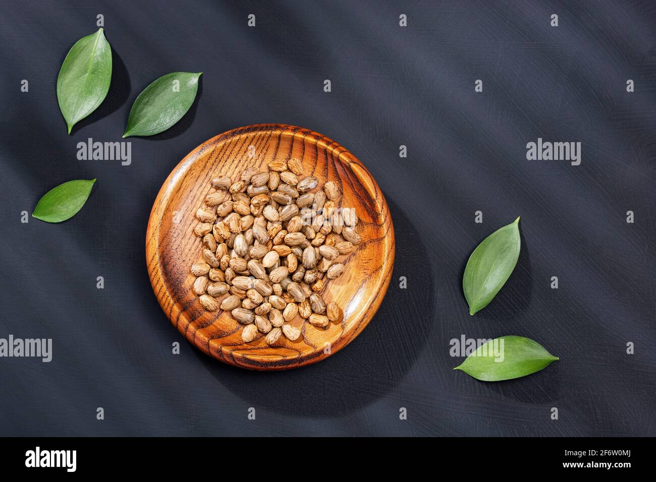 Ricinus communis seeds in the wooden bowl Stock Photo