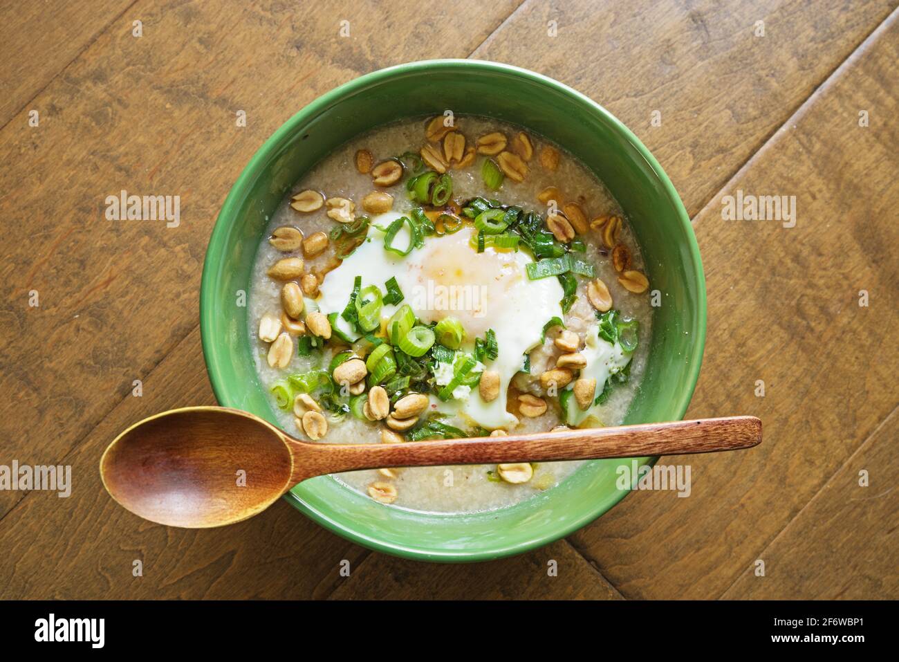 bowl of congee or rice porridge with fried egg green onions and peanuts Stock Photo