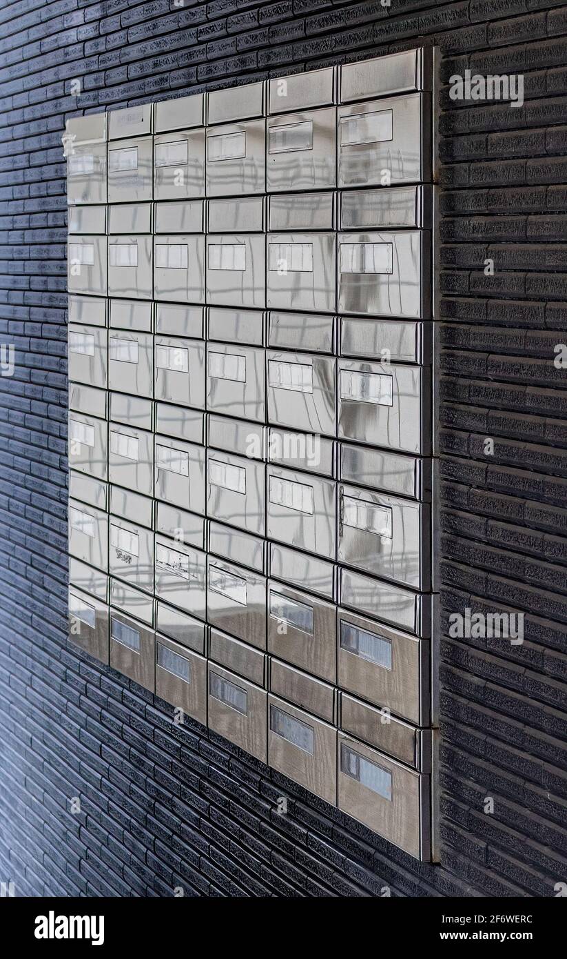 Rows of 24 shiny mailboxes at the outside wall of an apartment complex