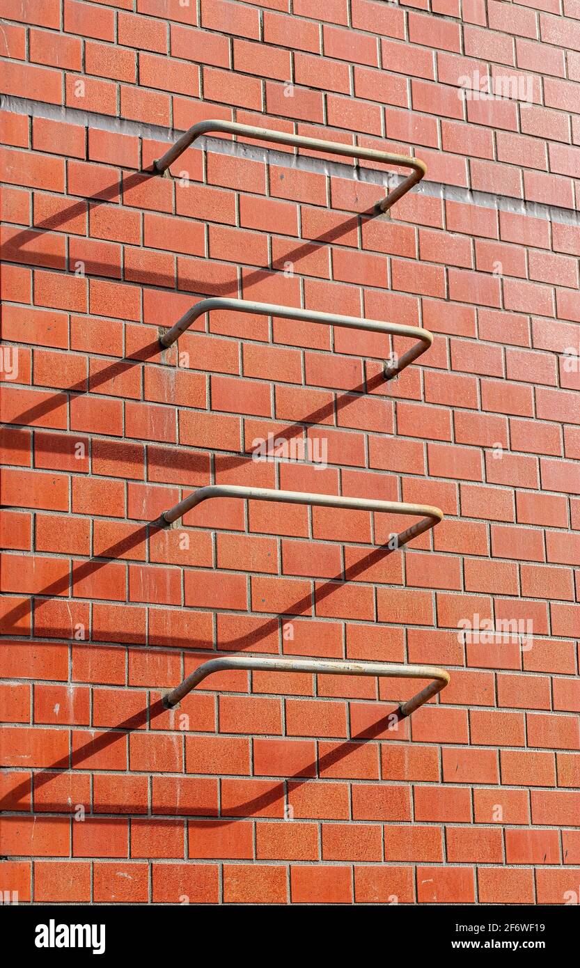 4 iron bars that are part of an escape ladder in case of a fire, are caught in the setting sun. The shadows make it look like 3 bent rectangles and 1 Stock Photo