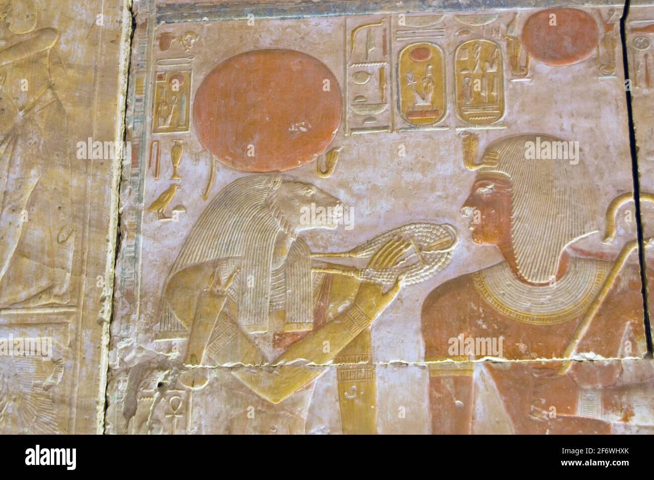 Ancient egyptian painted hieroglyphic carving of the lioness headed goddess Sekhmet with the Pharoah Seti. Inner wall of the Temple to Osiris at Abydo Stock Photo