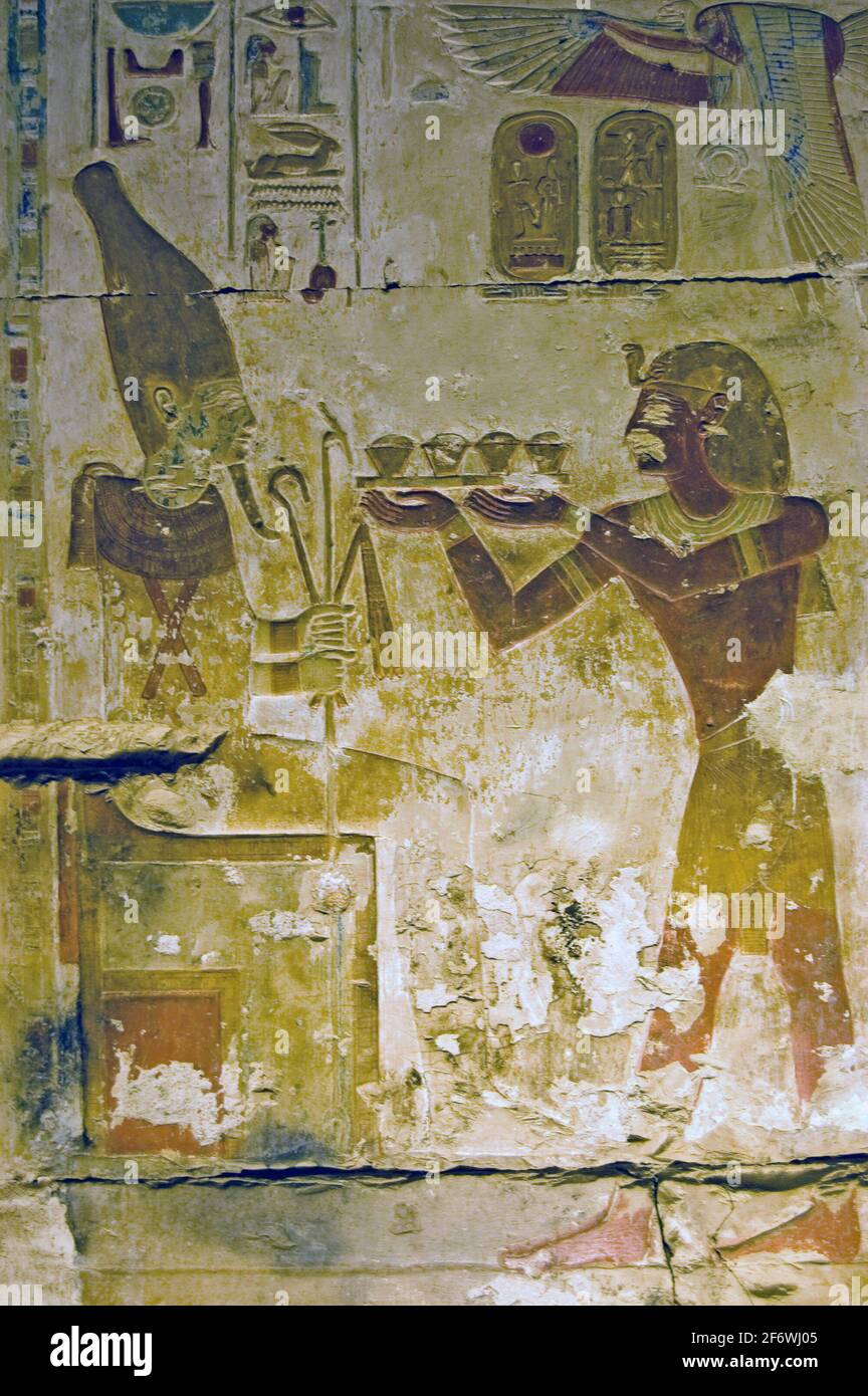 Ancient egyptian hieroglyphic painted carving showing the Pharoah Seti making an offering to the god of regeneration Osiris. Temple of Osiris, Abydos, Stock Photo