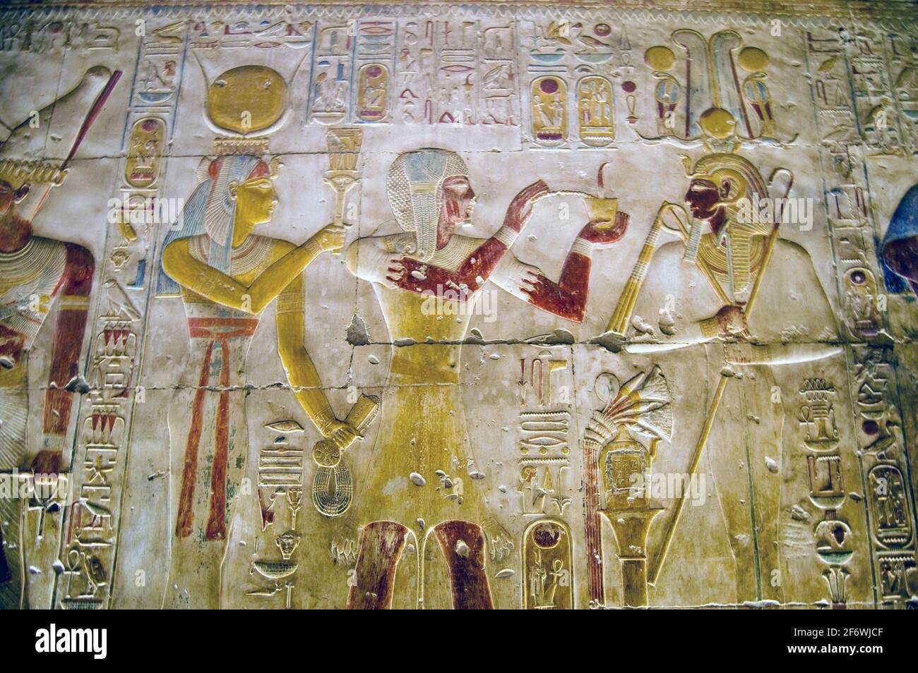 Ancient Egyptian hieroglyphic carving on an interior wall of the Temple of Abydos.  Showing the goddess Hathor on the left hand side, the god Osiris o Stock Photo