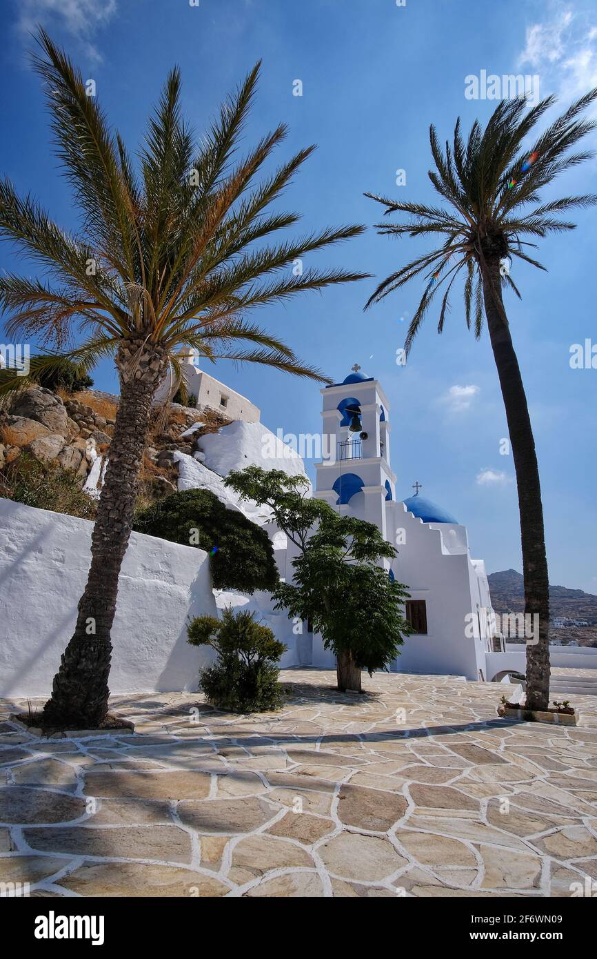 Beautiful whitewashed church next to palm trees in Ios cyclades Greece Stock Photo