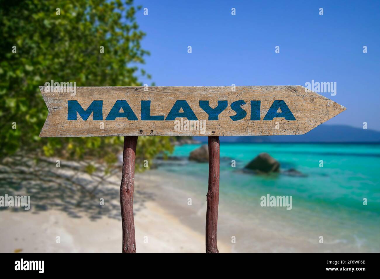 Malaysia wooden arrow road sign against beach with white sand and turquoise water background. Travel to Malaysia concept. Stock Photo