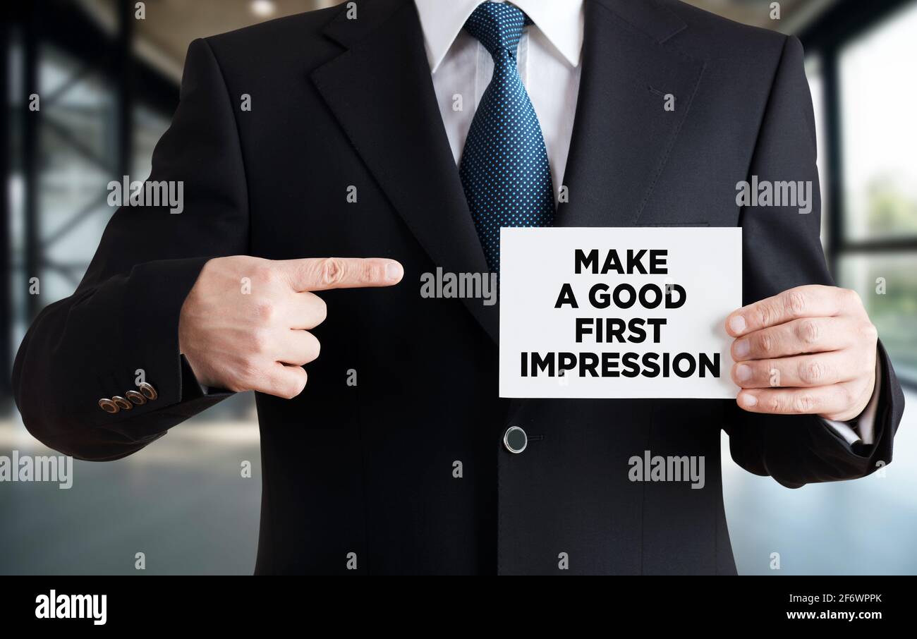 Businessman shows a card with the message make a goof first impression. Personal reputation in business concept. Stock Photo