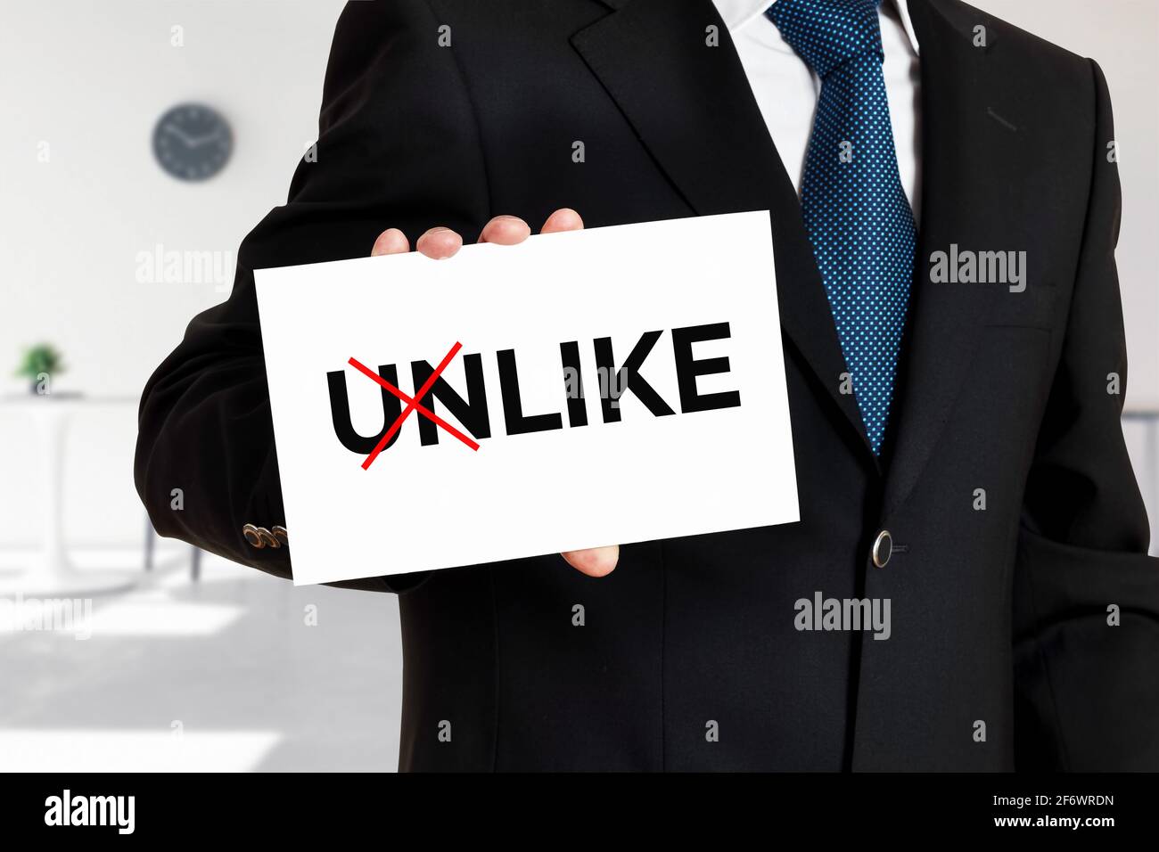 Businessman holds a card with the word unlike transformed into like. Stock Photo