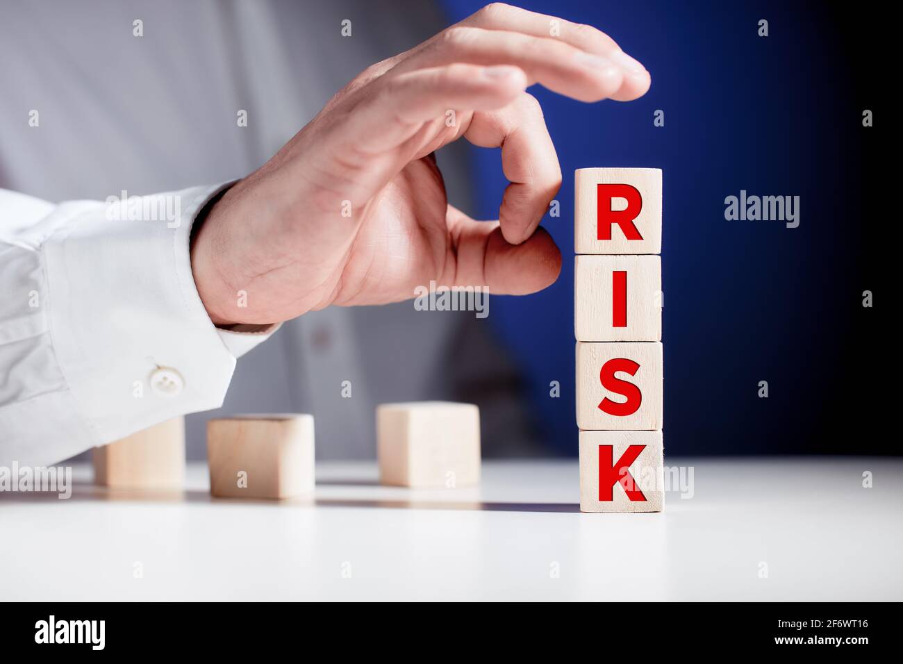 Businessman hand is about to flick the wooden cubes with the word risk. To avoid or eliminate risk in business finance decisions. Stock Photo