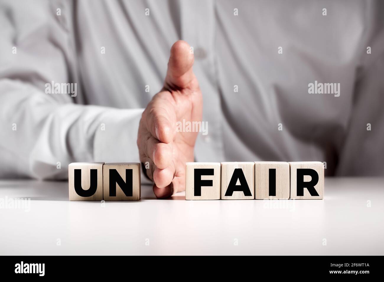 Businessman hand puts away the first two letters from the word unfair and transforms it into fair. Justice and fairness in business concept. Stock Photo