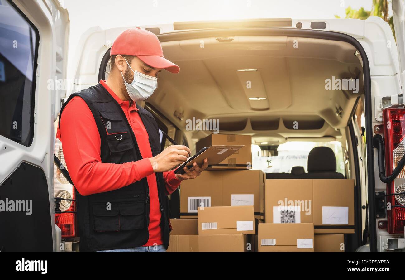 Delivery man wearing face protective mask working during corona virus outbreak - Express courier and online buying concept Stock Photo