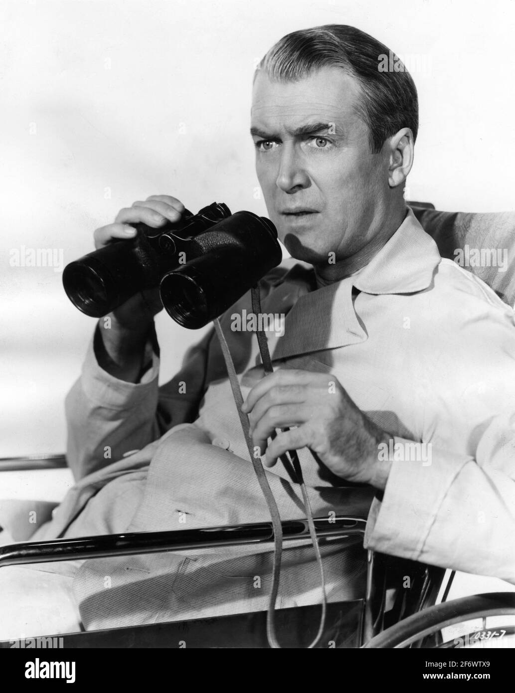 JAMES STEWART with Binoculars in REAR WINDOW 1954 director ALFRED HITCHCOCK screenplay John Michael Hayes based on a short story by Cornell Woolrich Alfred J. Hitchcock Productions / Paramount Pictures Stock Photo