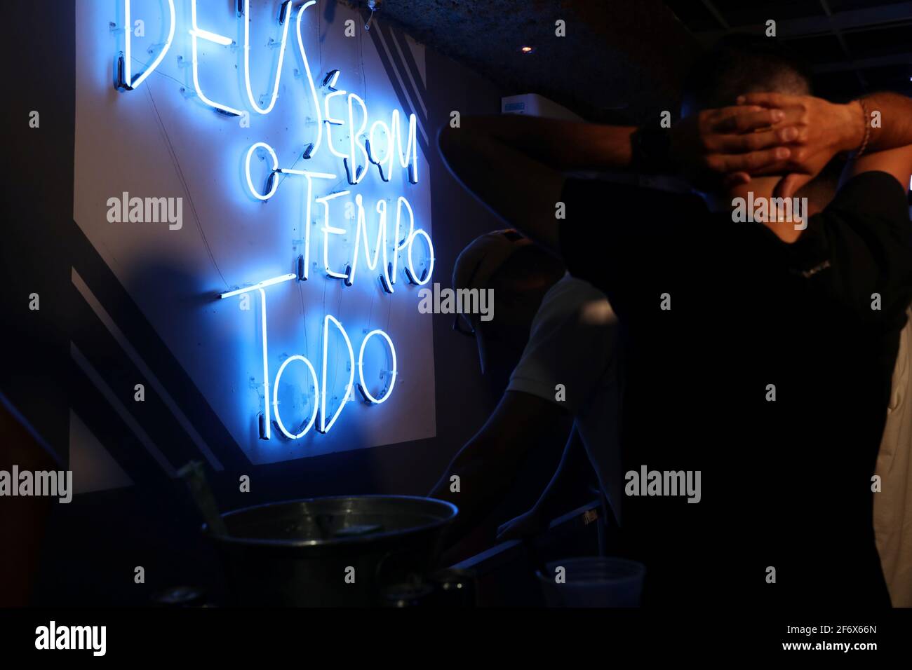 A man raises his hands near a neon light that reads 'God is good all the time' in a night club during a civil police operation tackling COVID-19 restrictions violations, amid a rise in coronavirus disease cases and deaths in Sao Paulo, Brazil April 2, 2021. Picture taken April 2, 2021. REUTERS/Amanda Perobelli Stock Photo