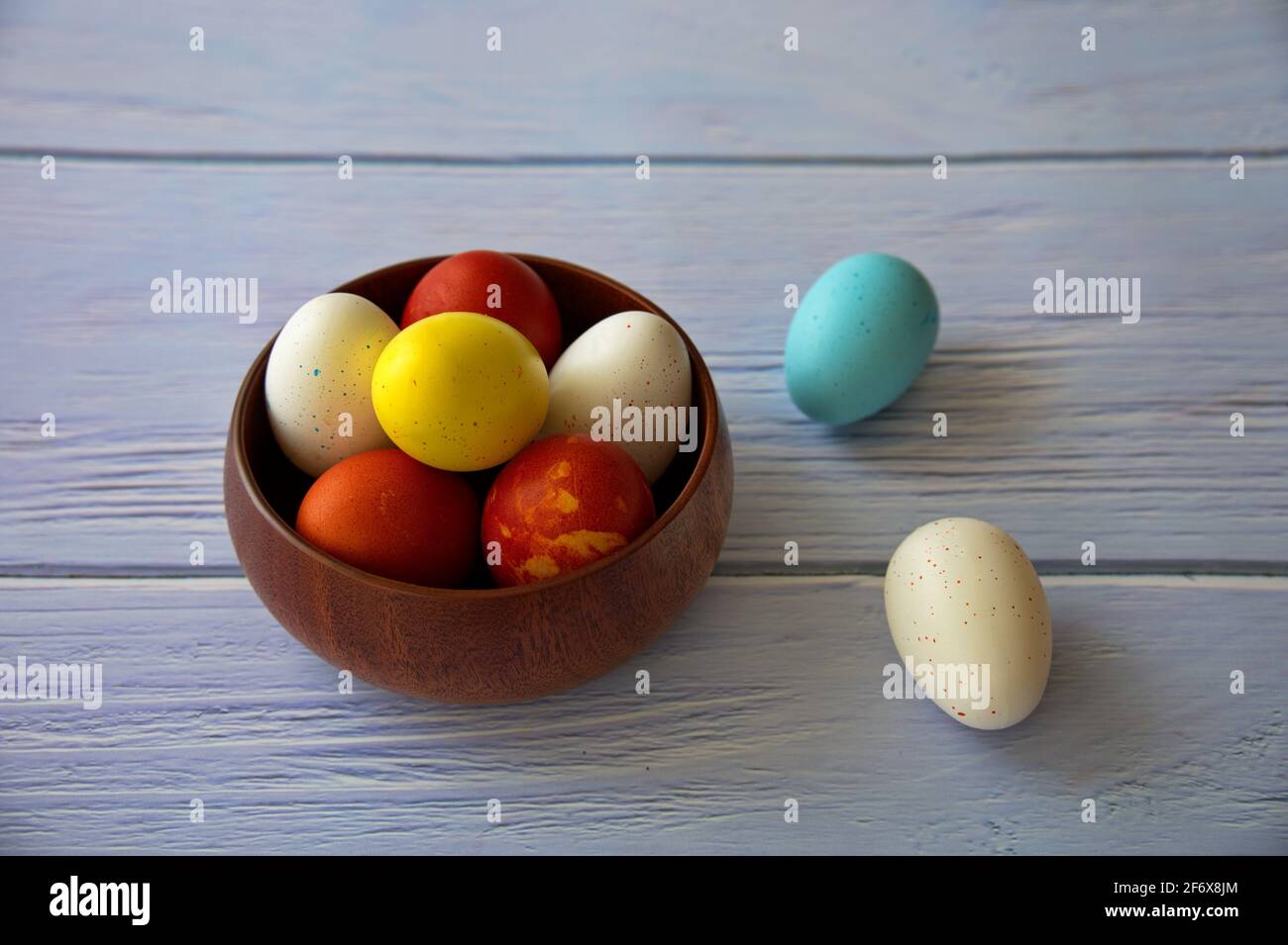 Colorful Easter eggs in wooden bowl on wooden background Stock Photo