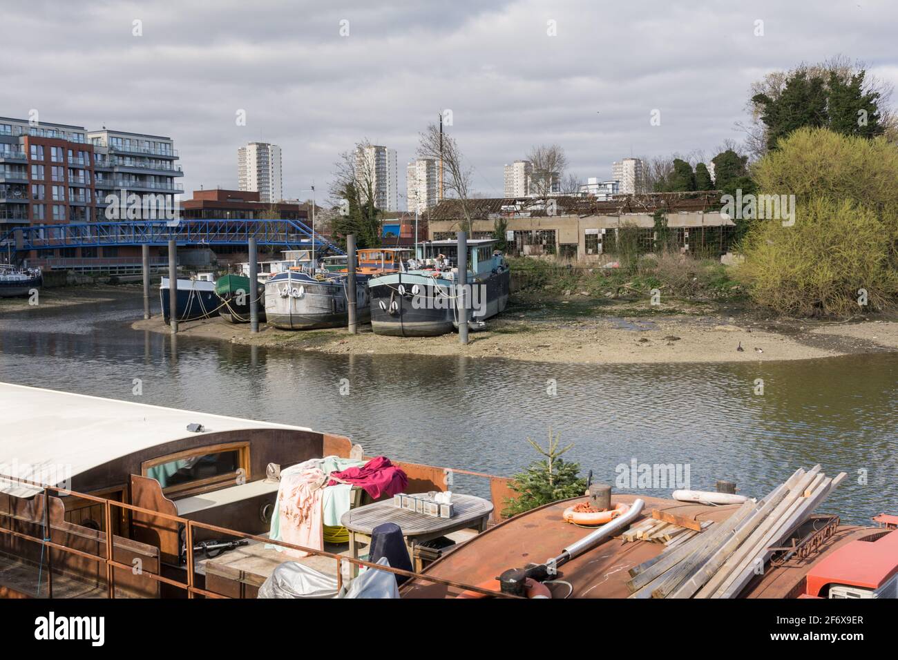 John’s Boat Works Ltd- colourful houseboats being repaired on Lot's Ait on the River Thames opposite the Waterman's Arts Centre, Brentford, London, UK Stock Photo
