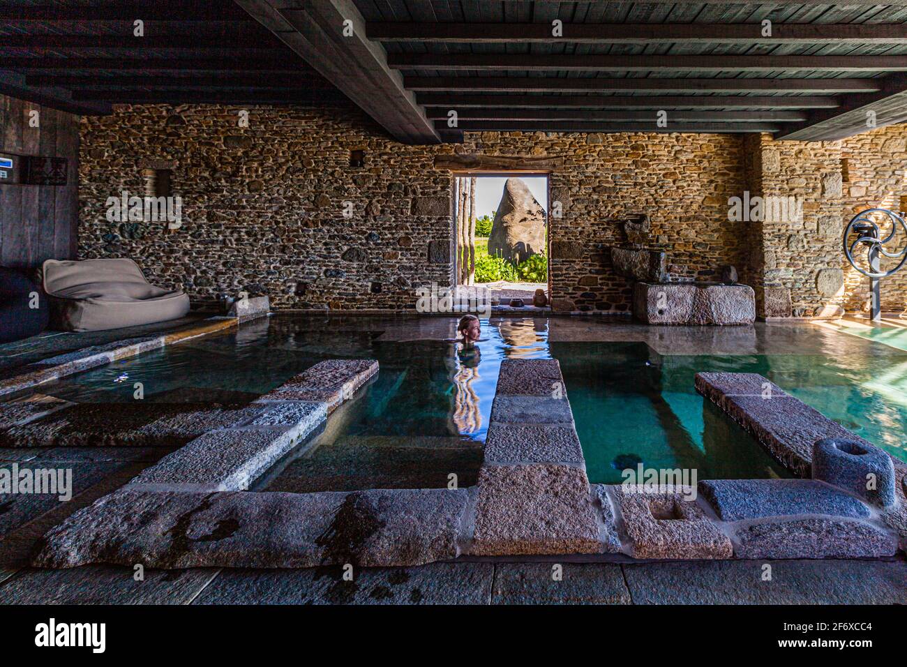 A huge menhir outside the window and inside the gentle roughness of the stone surfaces in the warm water Stock Photo
