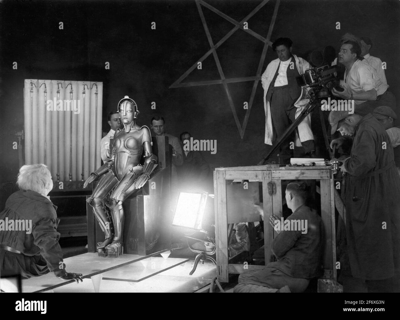 Director FRITZ LANG and Cinematographer KARL FREUND (in long coat on platform) with Movie Crew directing RUDOLF KLEIN-ROGGE as the Inventor and BRIGITTE HELM as the Robot on set candid during making of METROPOLIS 1927 director FRITZ LANG novel and screenplay Thea von Harbou Universum Film (UFA) Stock Photo