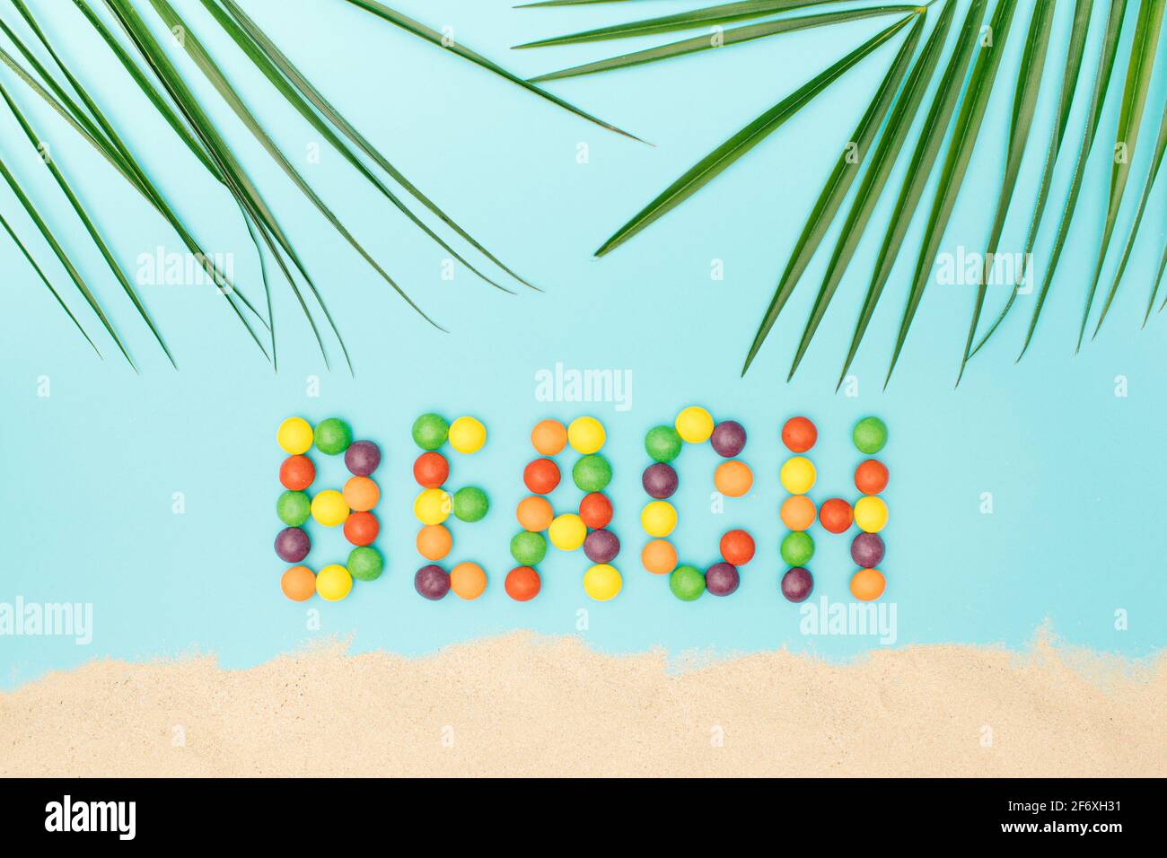 Beach with sand and palm leaves on a blue background. Tropical summer ...