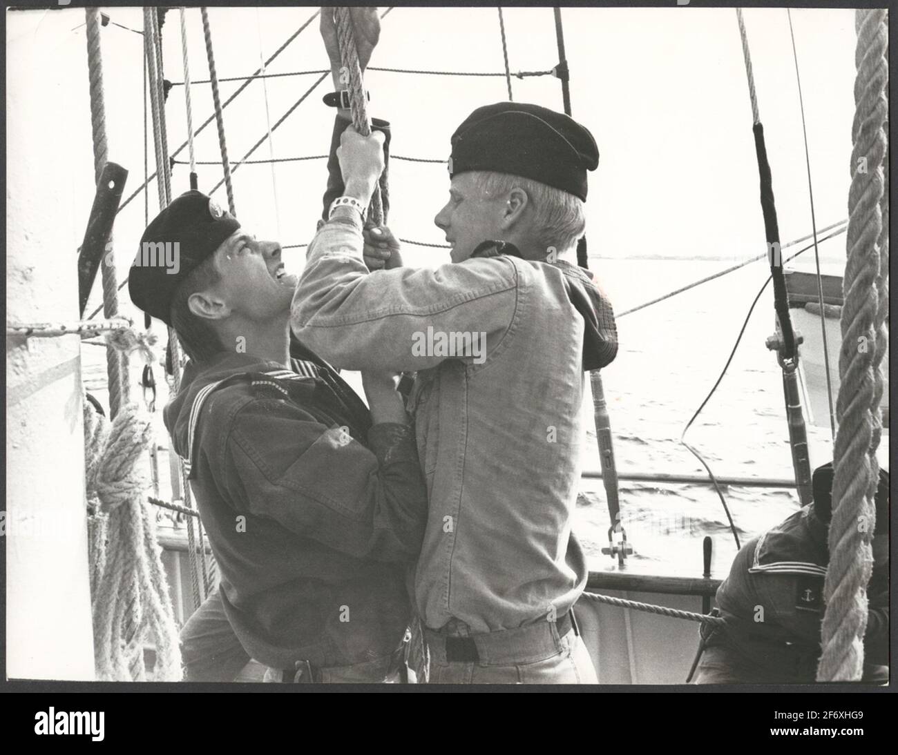 The picture shows two cadets on one of the marine school ships that are dragging on a rope or case.Probably it puts them a sail .. The picture shows two cadets on one of the marine school ships that are dragging on a rope or case.Likely to put them a sail. Stock Photo