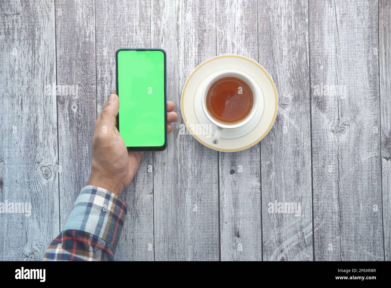 Top view of man hand holding smart phone and drinking tea  Stock Photo