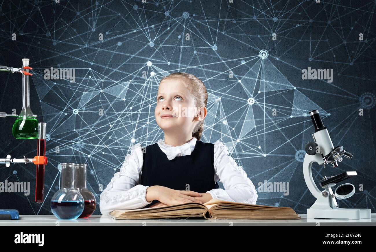 Smiling little girl sitting at desk with open book Stock Photo - Alamy