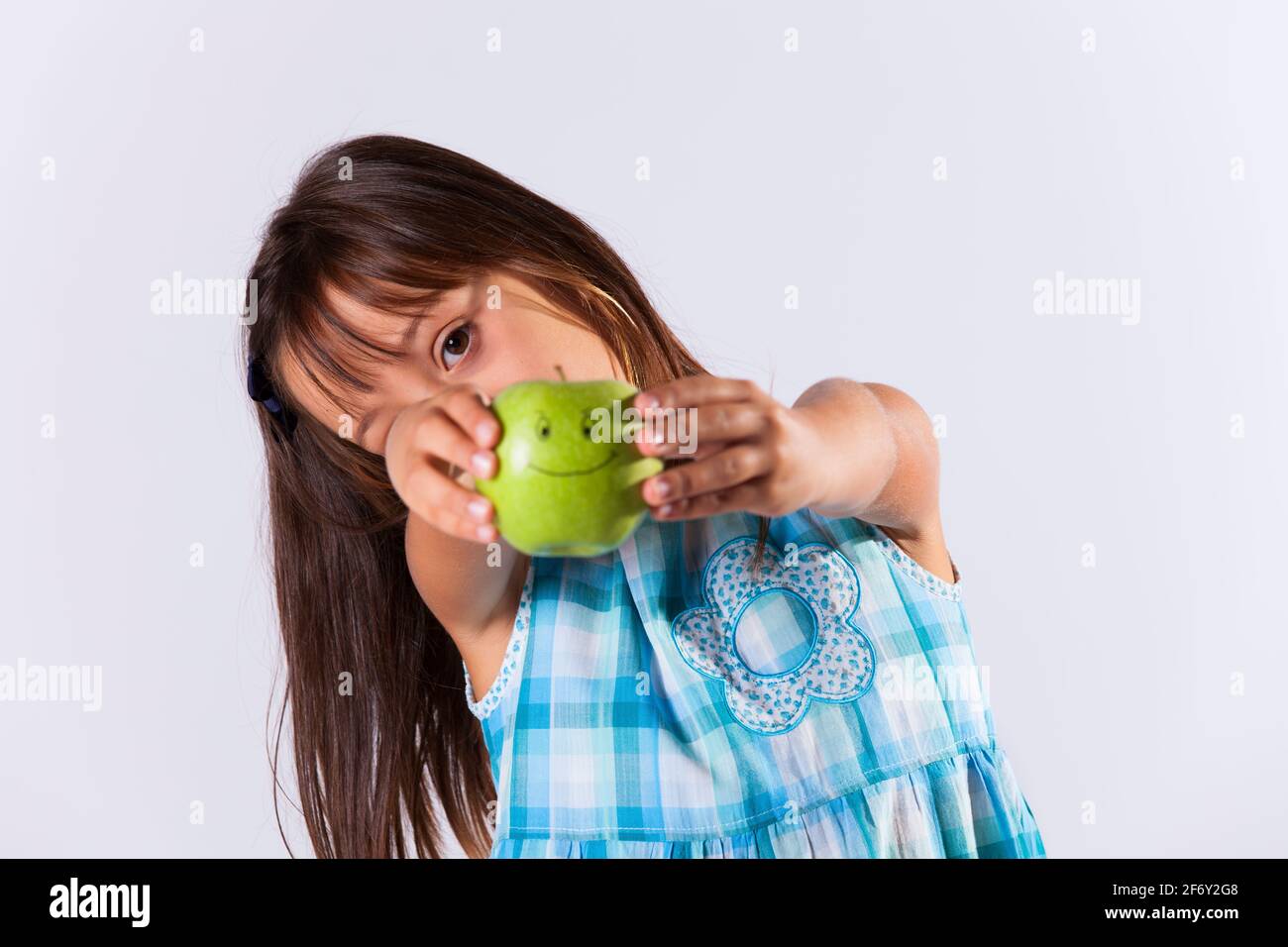 Little girl showing a green apple with a smile Stock Photo