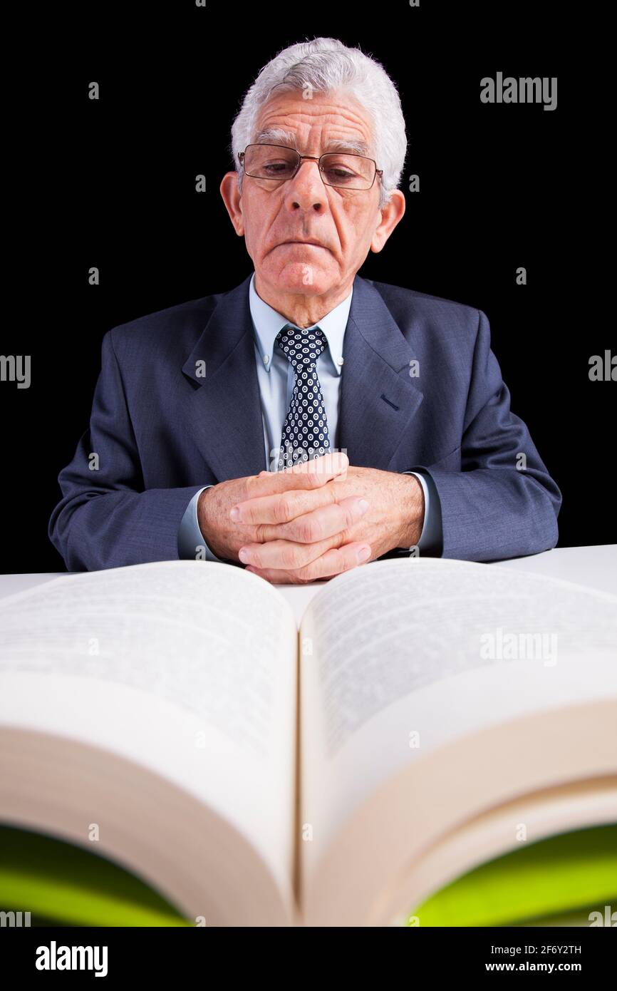 Senior businessman holding a page from an open book (isolated on black) Stock Photo