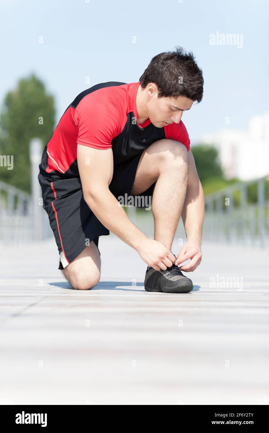 Athlete male at the city park tying the laces of his shoes Stock Photo