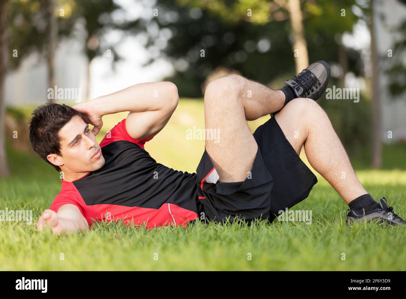 Athlete male at the city park making some abdominals Stock Photo