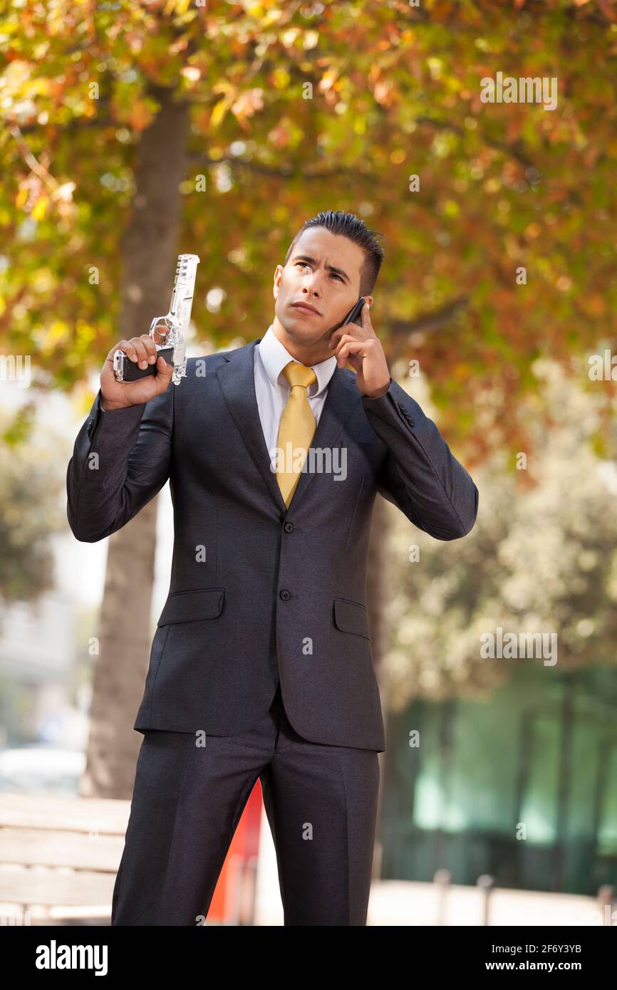 Powerful security businessman aiming a gun and calling at the cellular Stock Photo
