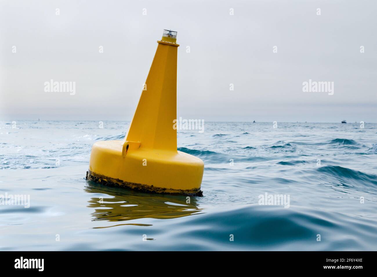 Yellow navigational sea buoy in the waves in the marina near Dubai Stock Photo
