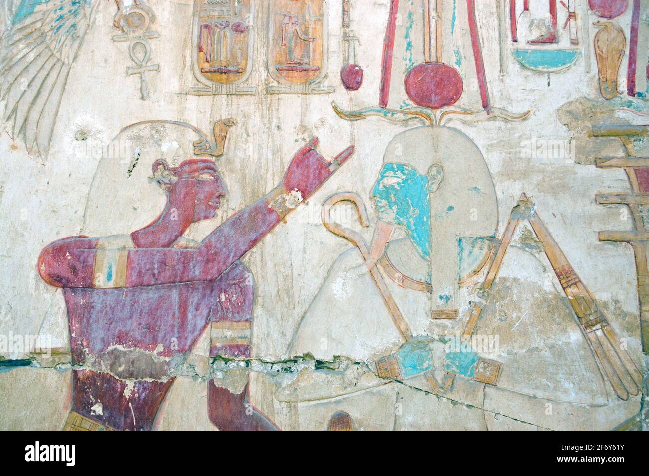 Ancient egyptian painted hieroglyphic carving of the Pharoah Seti with the god of regeneration Osiris. Wall at the Temple to Osiris at Abydos, Egypt. Stock Photo