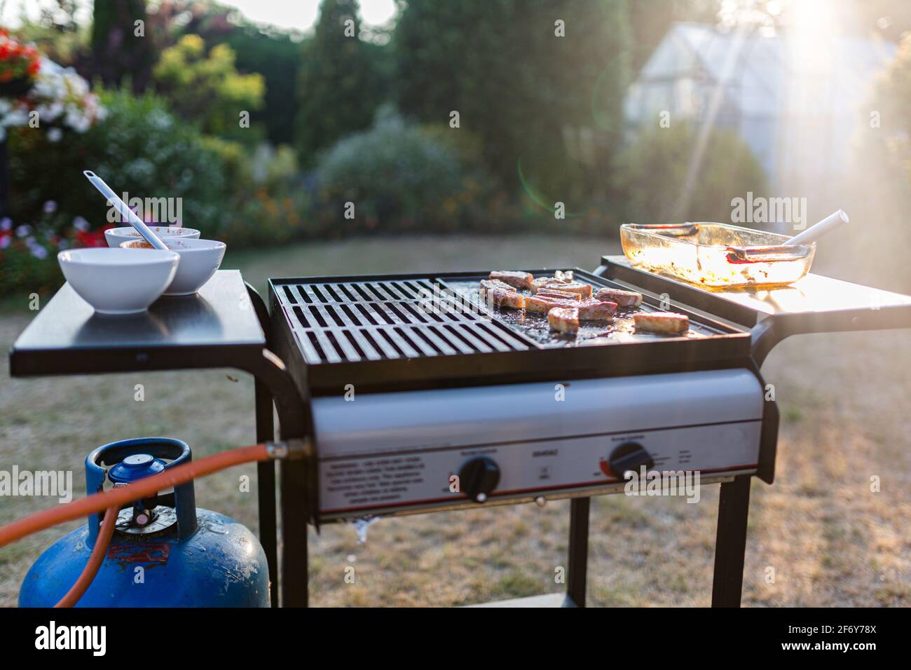 A traditional gas bbq with a selection of meats cooking in the summer  sunshine Stock Photo - Alamy