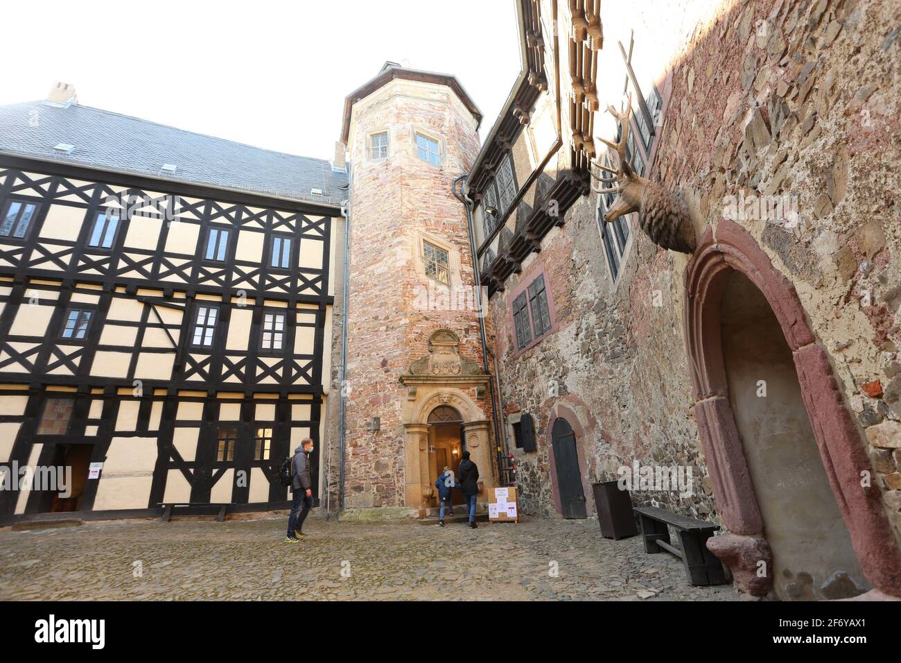 Pansfelde, Germany. 03rd Apr, 2021. Visitors standing in the courtyard. Falkenstein Castle in the southern Harz region was reopened to visitors for the first time after a long break due to the Corona pandemic. After booking by telephone, visitors can tour the castle grounds as well as experience a falconry demonstration. The castle is situated above the Selketal. The fortified complex was built at the beginning of the 12th century and passed as a fiefdom to the noble Asseburg family in the 15th century. Credit: Matthias Bein/dpa-Zentralbild/dpa/Alamy Live News Stock Photo