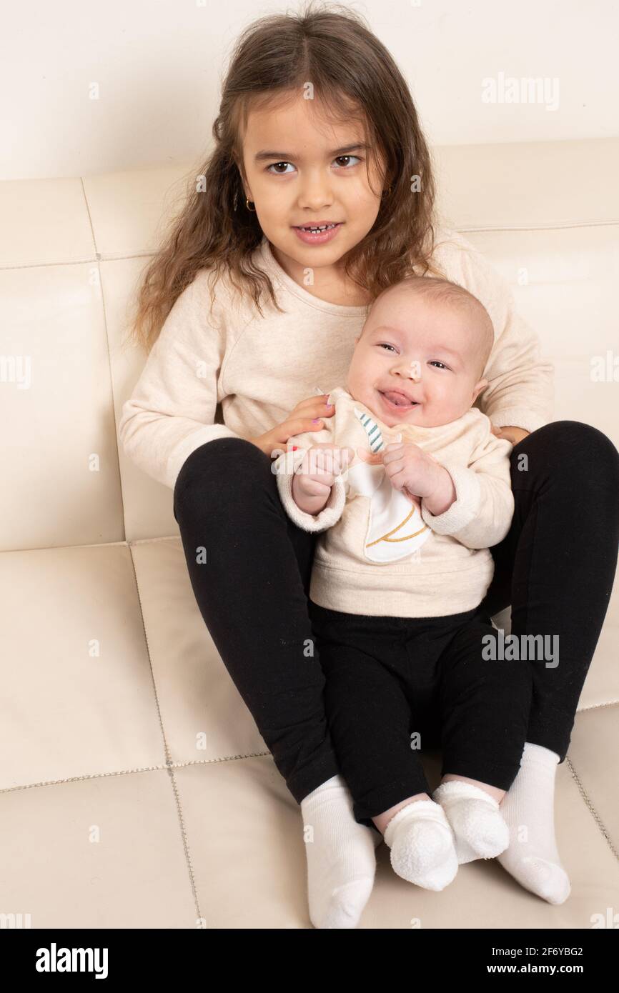 Four year old girl posing with two month old baby sister Stock Photo