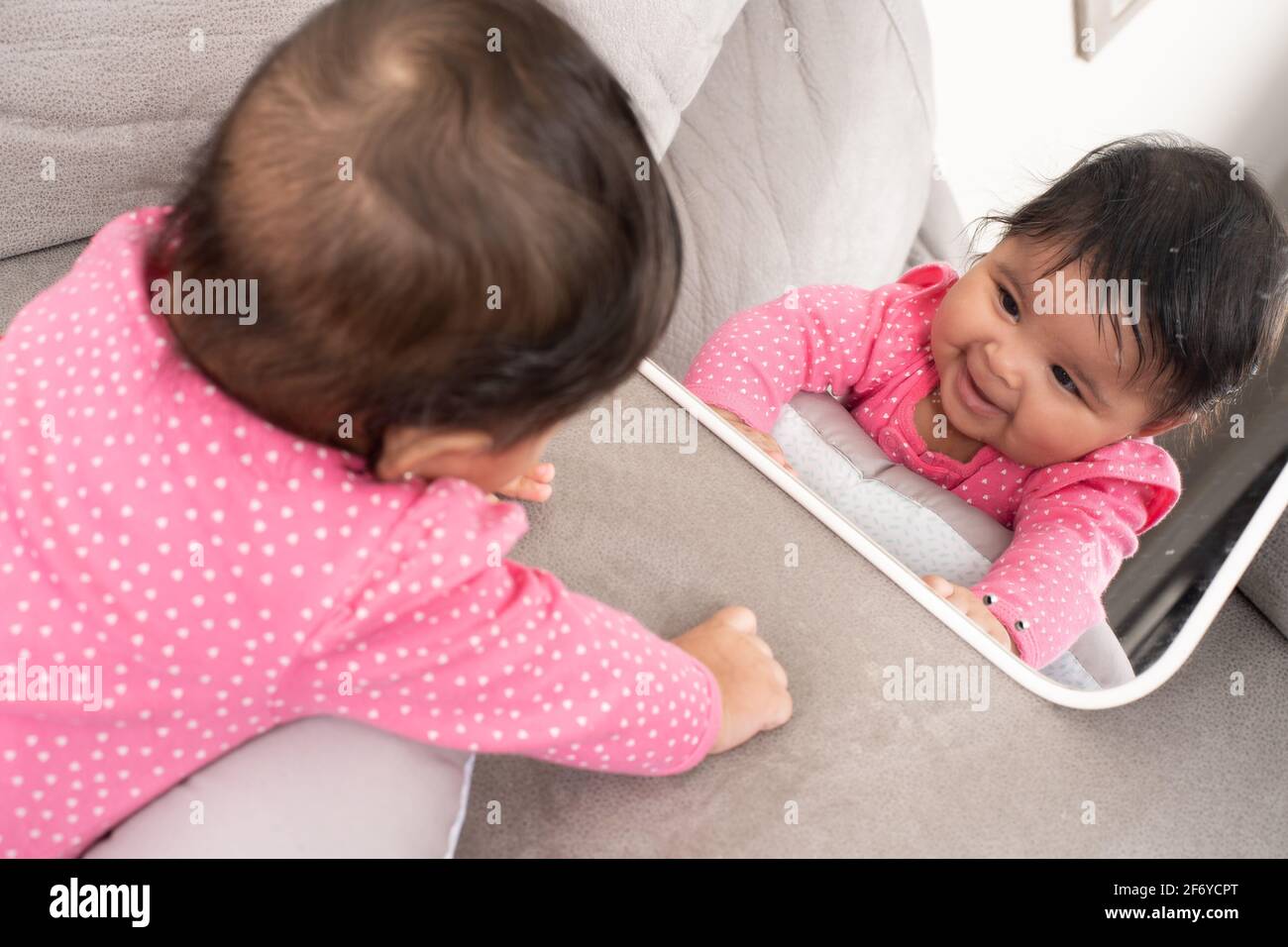 4 month old baby girl looking at self in mirror, smiling Stock Photo