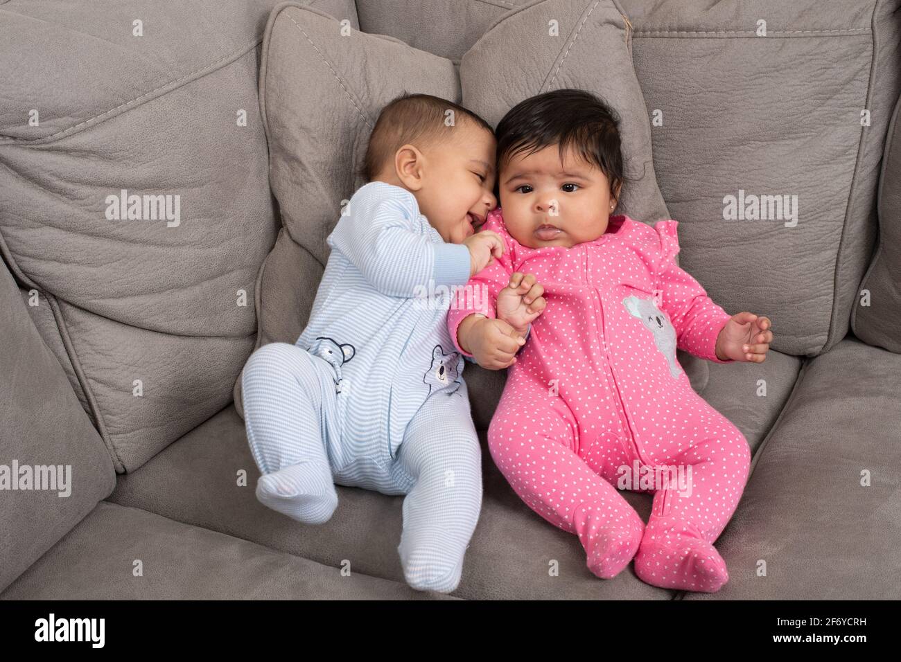 4 month old fraternal twins girl and boy propped up together on couch
